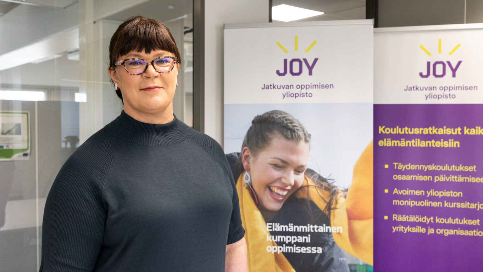 Henkilö seisoo jatkuvan oppimisen mainoksien vieressä.