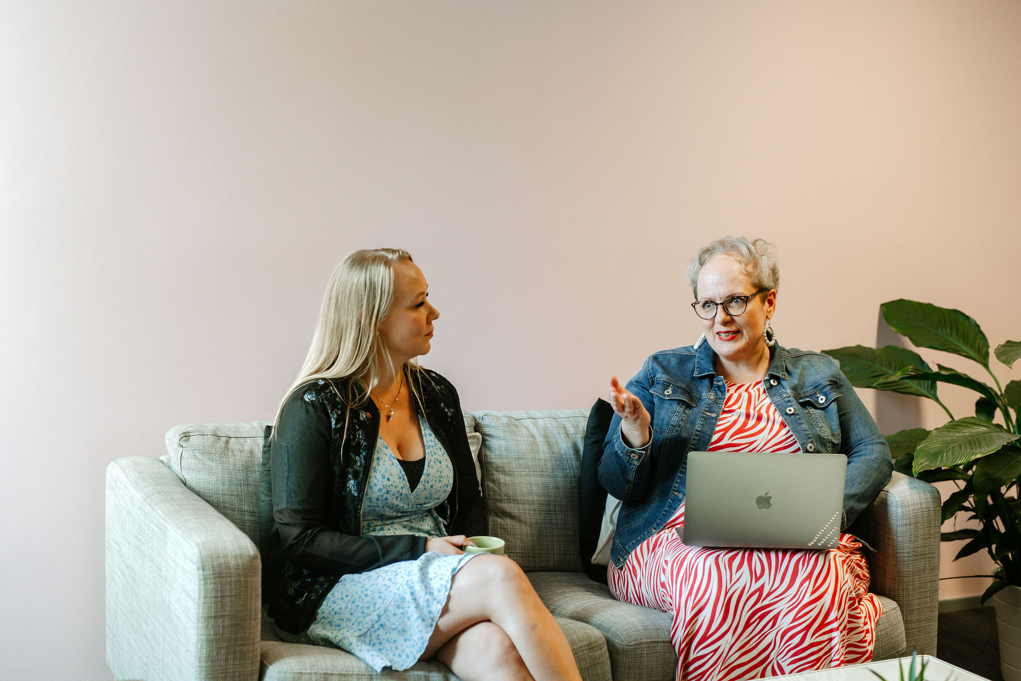Two people sit on a sofa and have a conversation.