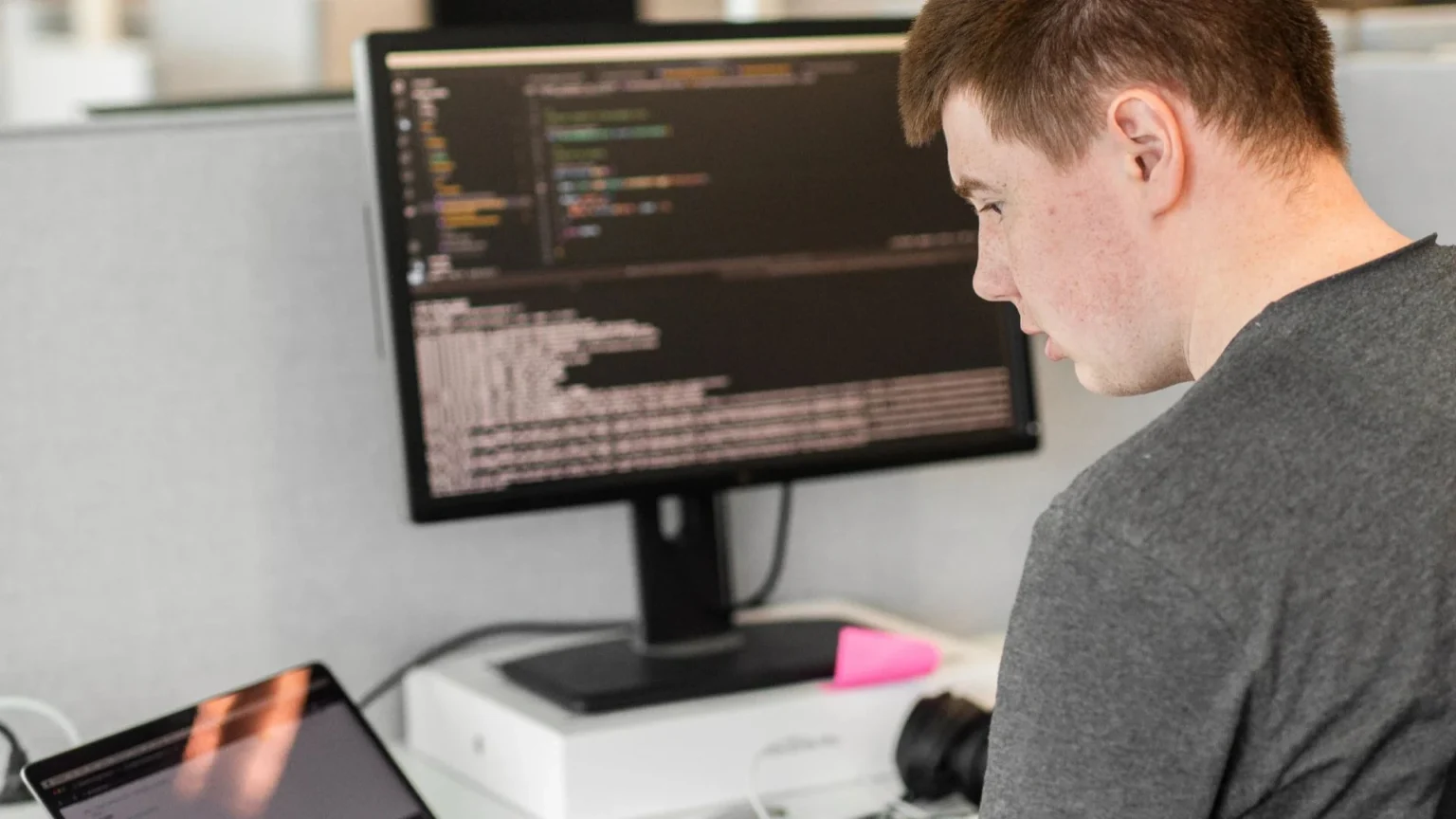 Henkilö tekee tietokoneella koodaustyötä.